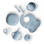 Collection of baby utensils including a bowl, spoon, fork, bib, and cup on a white background.