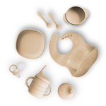 Collection of baby utensils including bowls, cup, spoon, and bib on a white background