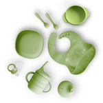 Set of green baby utensils including plate, cup, spoon, bib, and teether on a white background