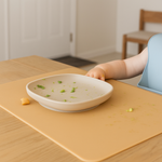 Child's hand reaching for a bowl on a yellow placemat 